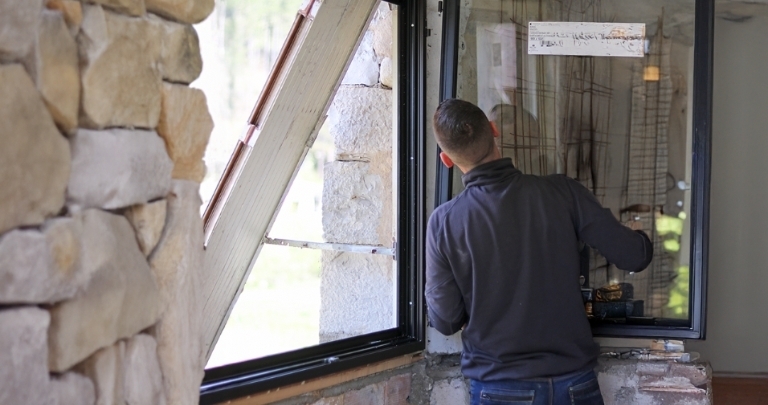 Homme qui prend les mesures d'une fenêtre lors d'une rénovation